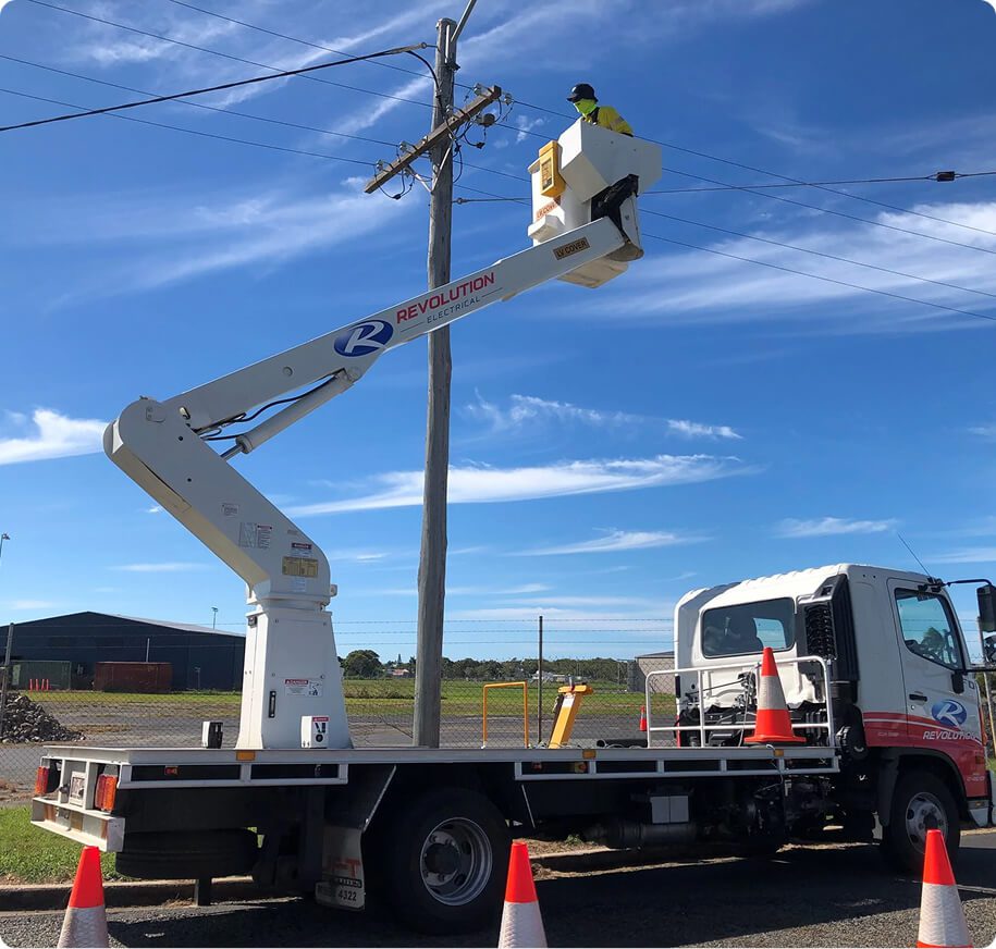 Traffic signal maintenance being carried out from an elevated work platform, with a technician accessing overhead lines and signal equipment.