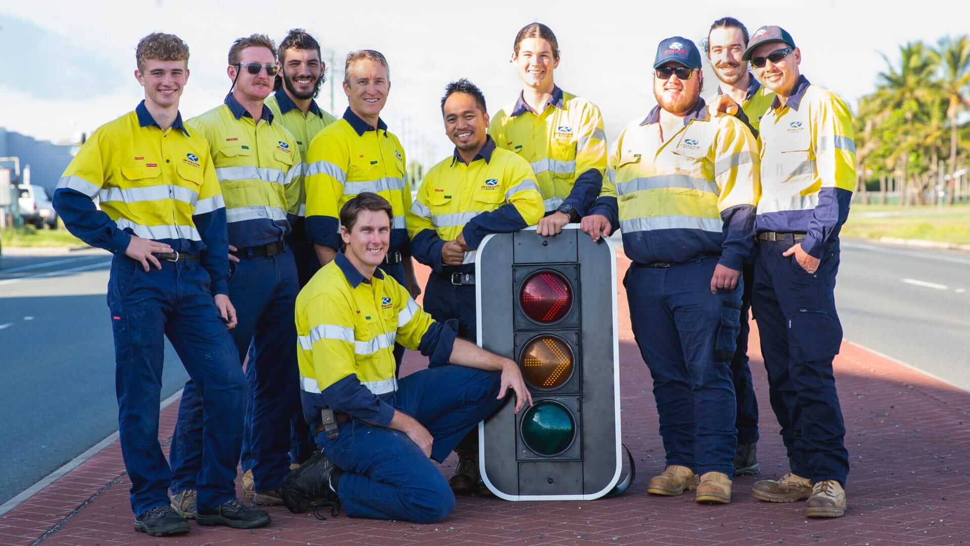 Revolution Electrical road services crew posing with a traffic signal head, showcasing team expertise in traffic signal installation and maintenance.